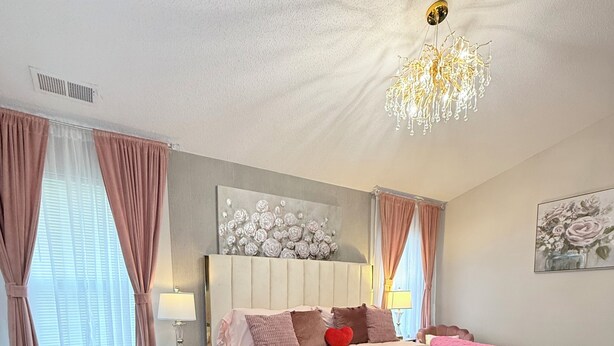 Ein Schlafzimmer mit einem großen Bett, einem Nachttisch, einer Lampe und einer Deckenleuchte.