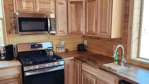 A kitchen with wooden cabinets, a stainless steel stove, a microwave, and a dishwasher. - The Rocky Mountain Cabin (Hurricane)