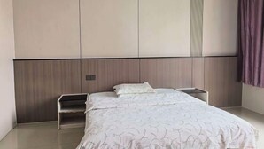 A bedroom with a bed, bedside tables, and a headboard. - Debao Hongshanyuan Hotel (Debao)