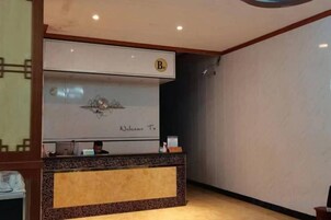 Una mesa de recepción con un cartel de 'Welcome To', un logotipo y una persona sentada detrás.