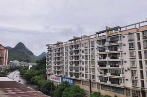 A multi-story residential building with balconies, a clear sky, and a mountain in the background.