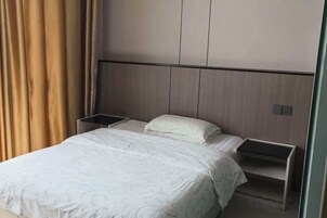 Una habitación de hotel con una cama, mesitas de noche y cabecero.