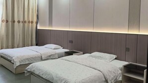 A bedroom with two beds, a bedside table, a nightstand, and a built-in wardrobe. - Debao Hongshanyuan Hotel (Debao)