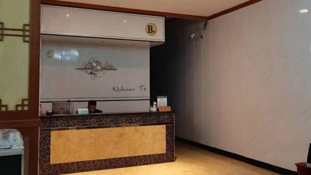 A reception area with a reception desk, a large clock, and a 'Welcome To' sign. - Debao Hongshanyuan Hotel (Debao)