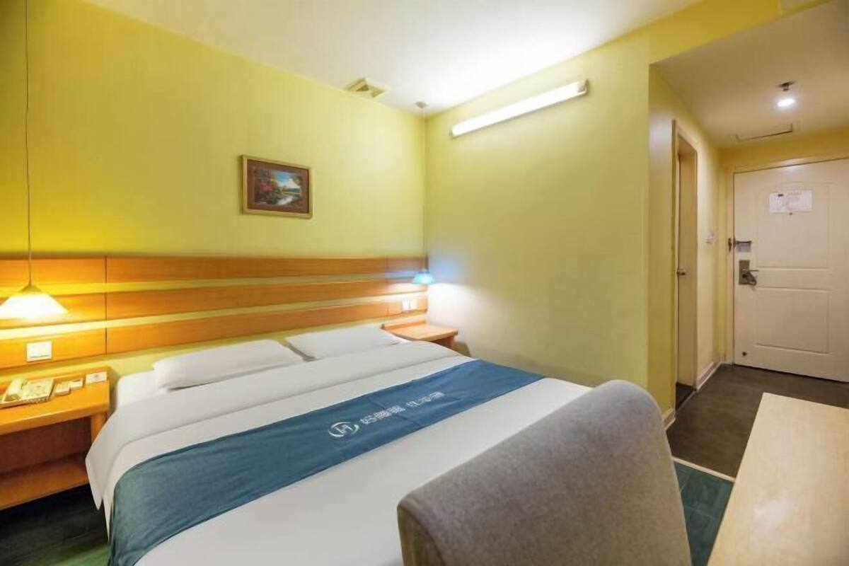Ein Hotelzimmer mit Bett, Nachttisch, Lampe und Tür.