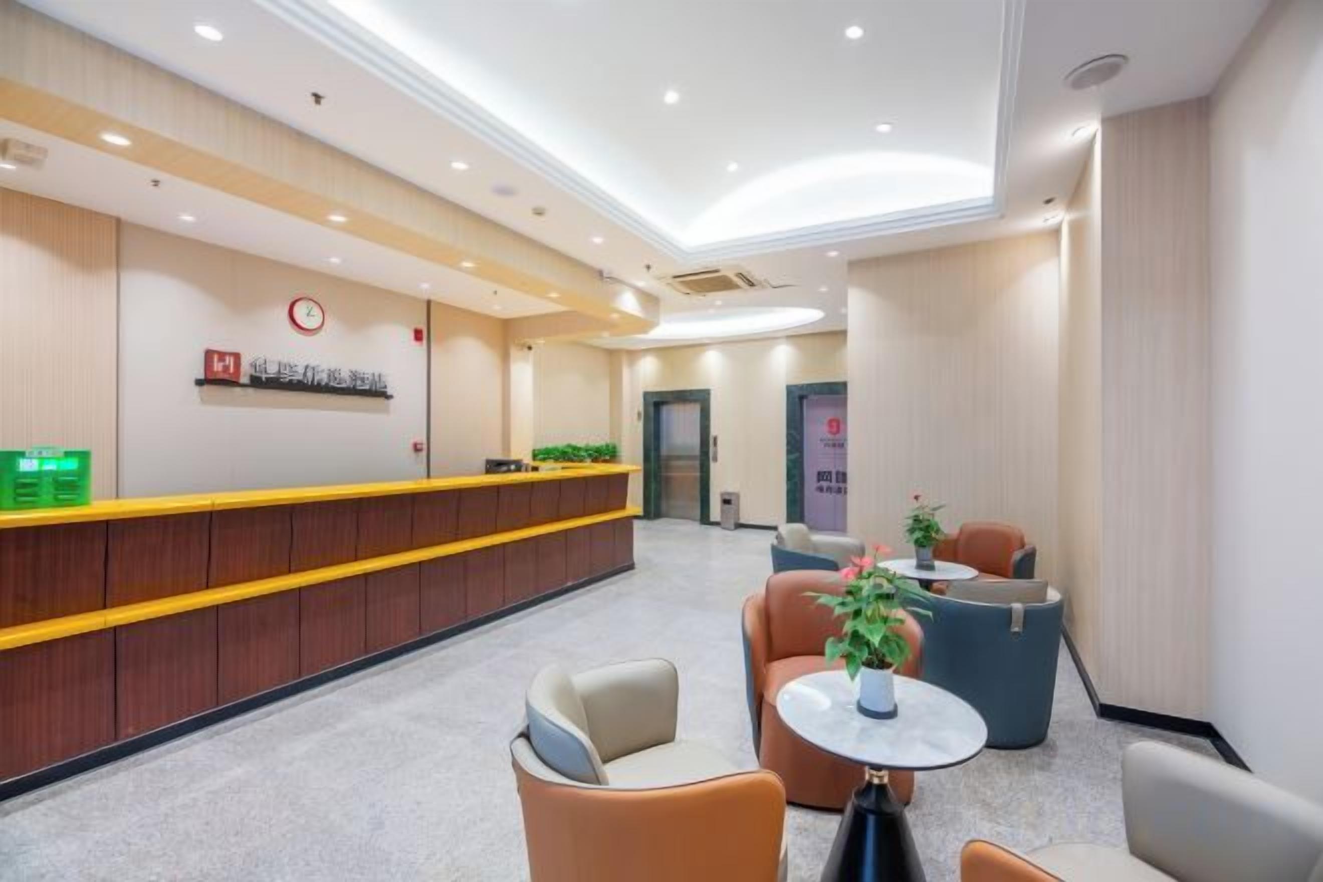 Zona de recepción de un hotel con mostrador, área de descanso y una puerta al fondo.