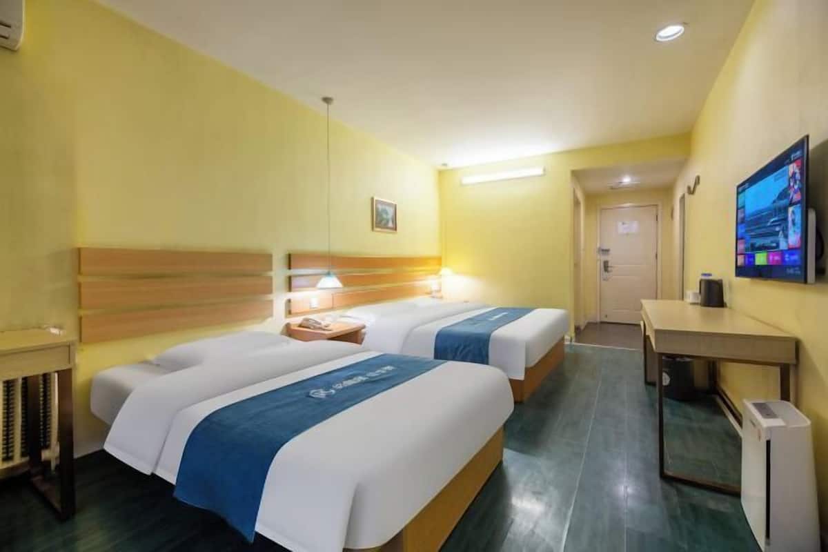 Ein Hotelzimmer mit zwei Betten, einem Schreibtisch, einem Sessel, einem Fernseher und einer Tür.