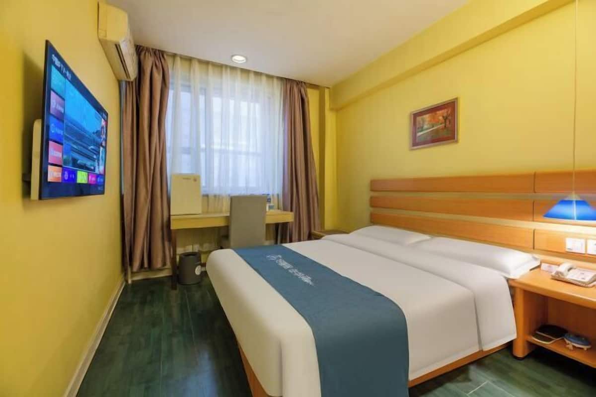 Ein Hotelzimmer mit einem Bett, einem Schreibtisch, einem Sessel, einem Fernseher und einem Bild an der Wand.