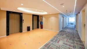 A hotel corridor with wooden panel walls, a patterned carpet, and a ceiling with recessed lighting. - Home Inn Plus Hotel (Shijiazhuang)