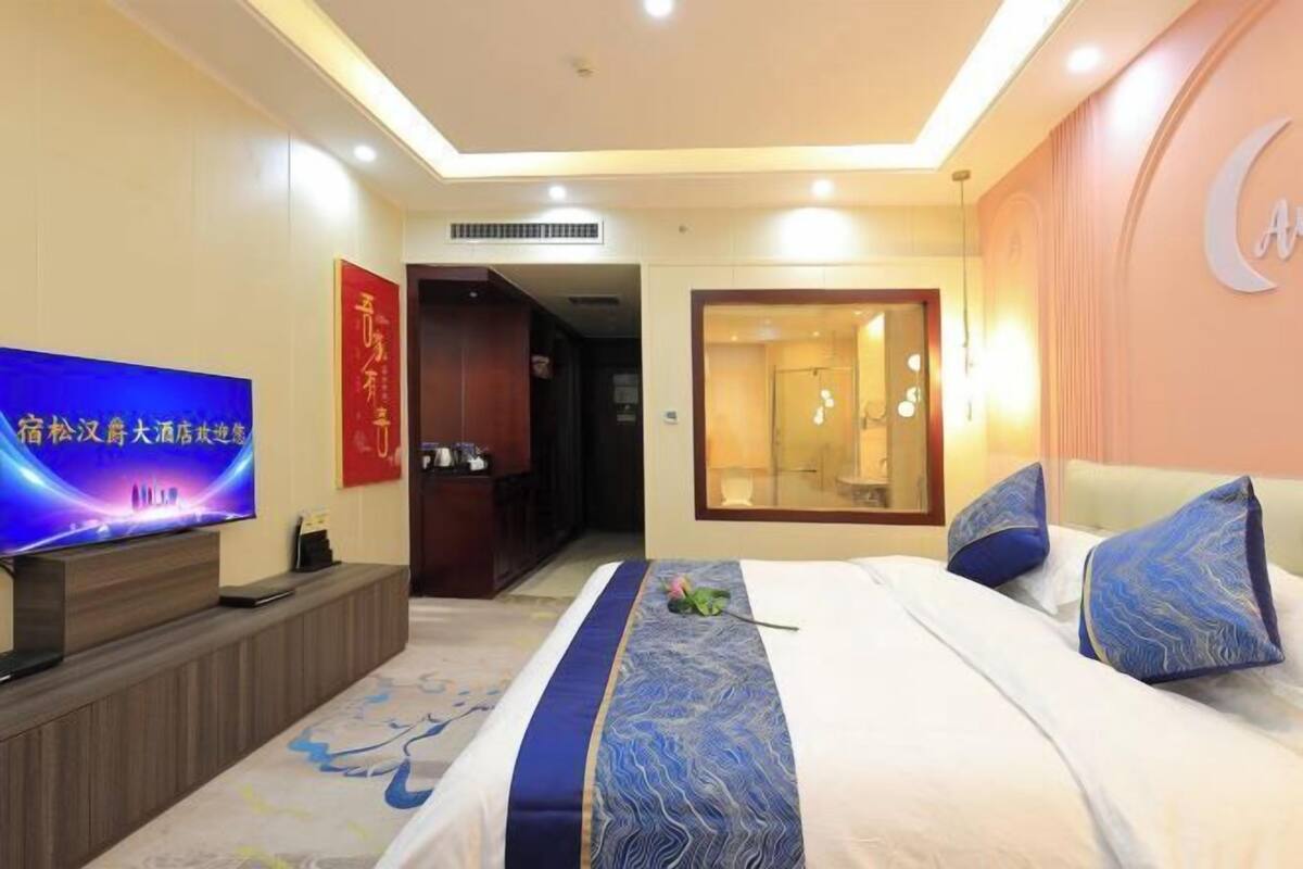 A hotel room with a bed, a TV, a desk, and a mirror.