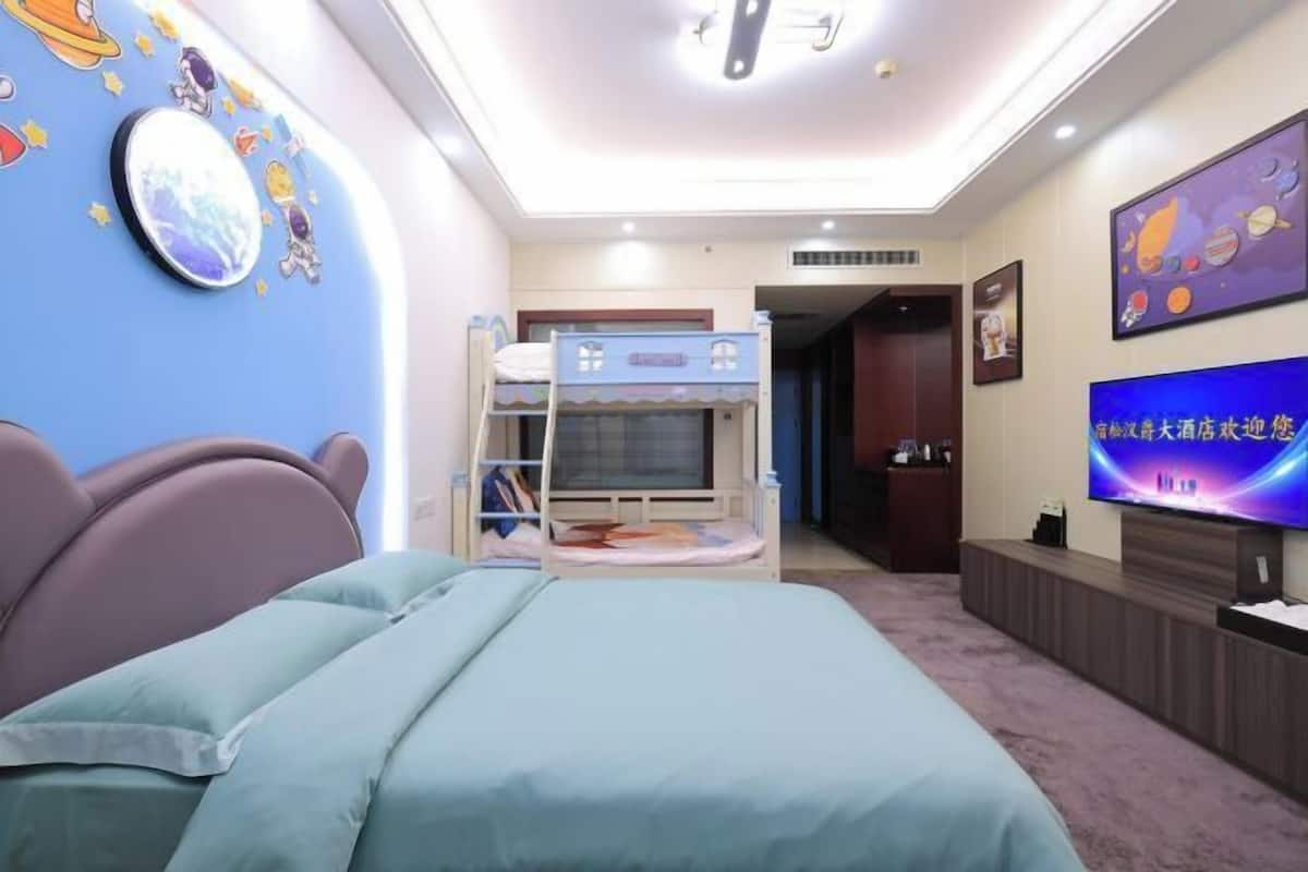 A bedroom with bunk beds, a television, and a wall with space-themed decorations.
