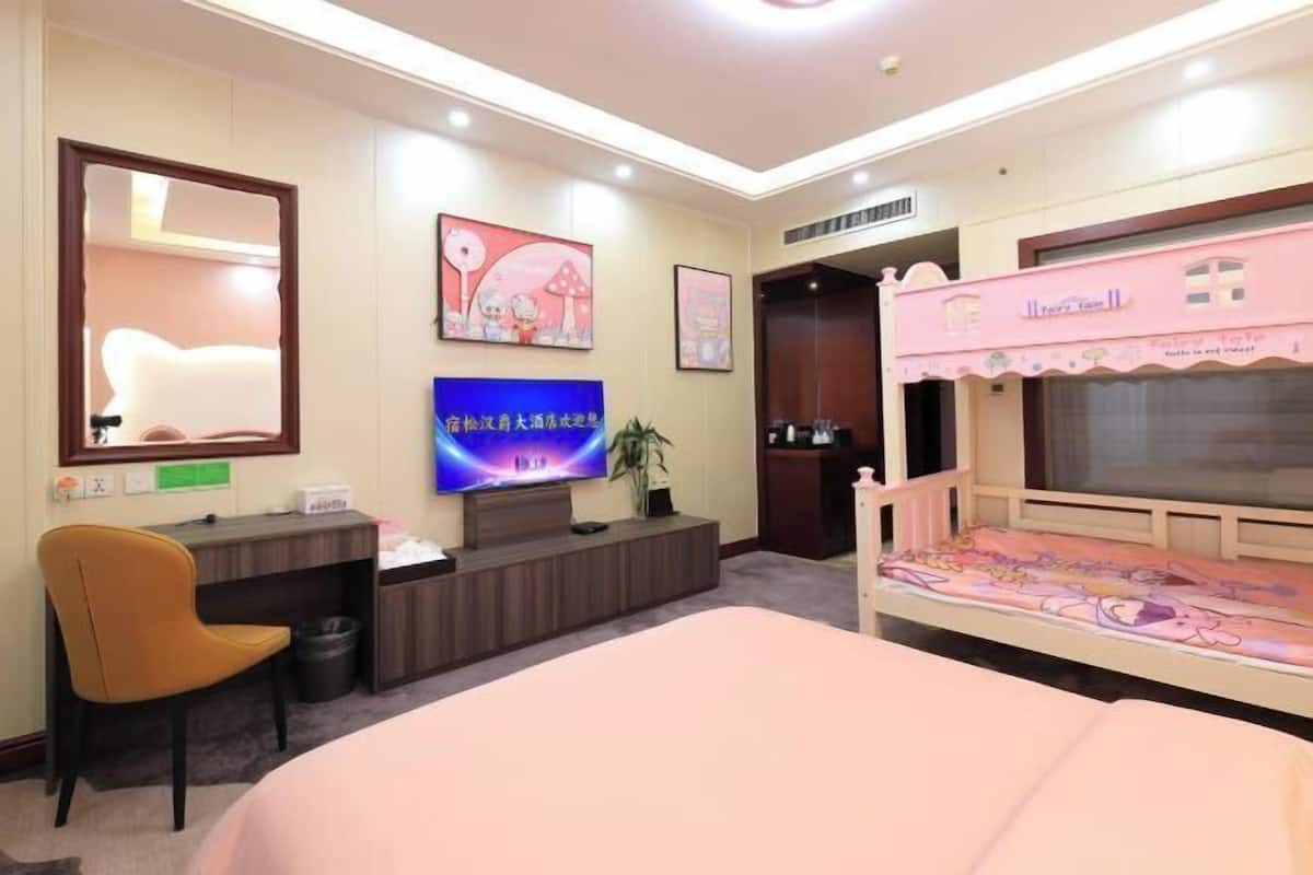 A hotel room with a bed, desk, chair, TV, and a pink wall decoration.