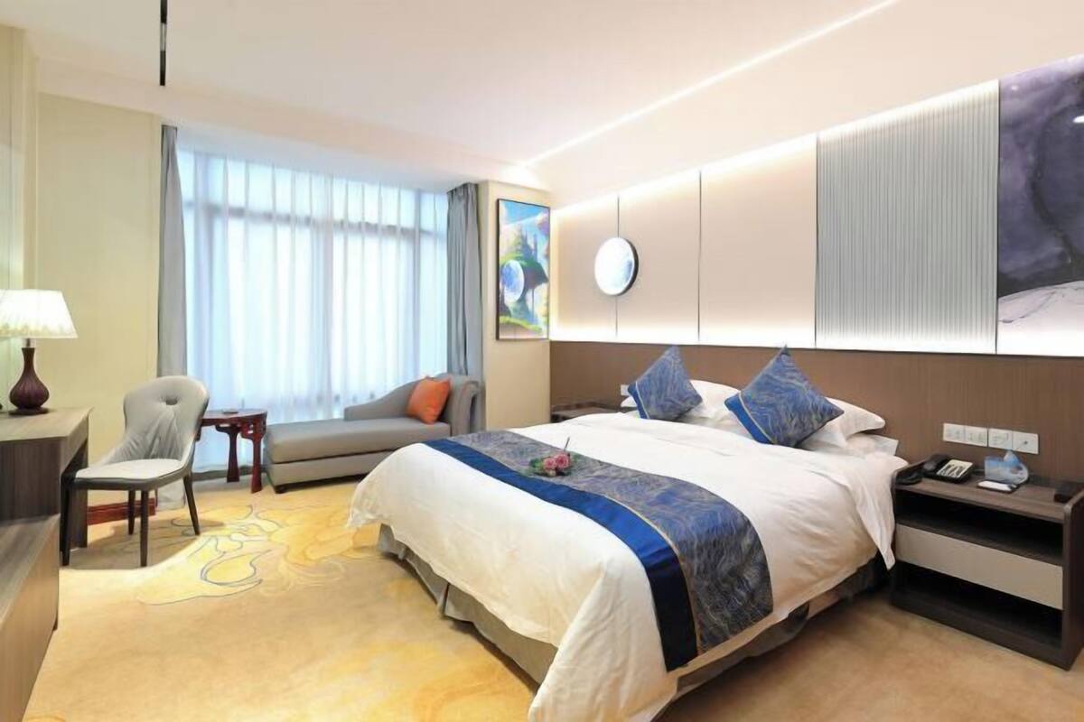 A hotel room with a large bed, a sofa, a desk, and a chair.