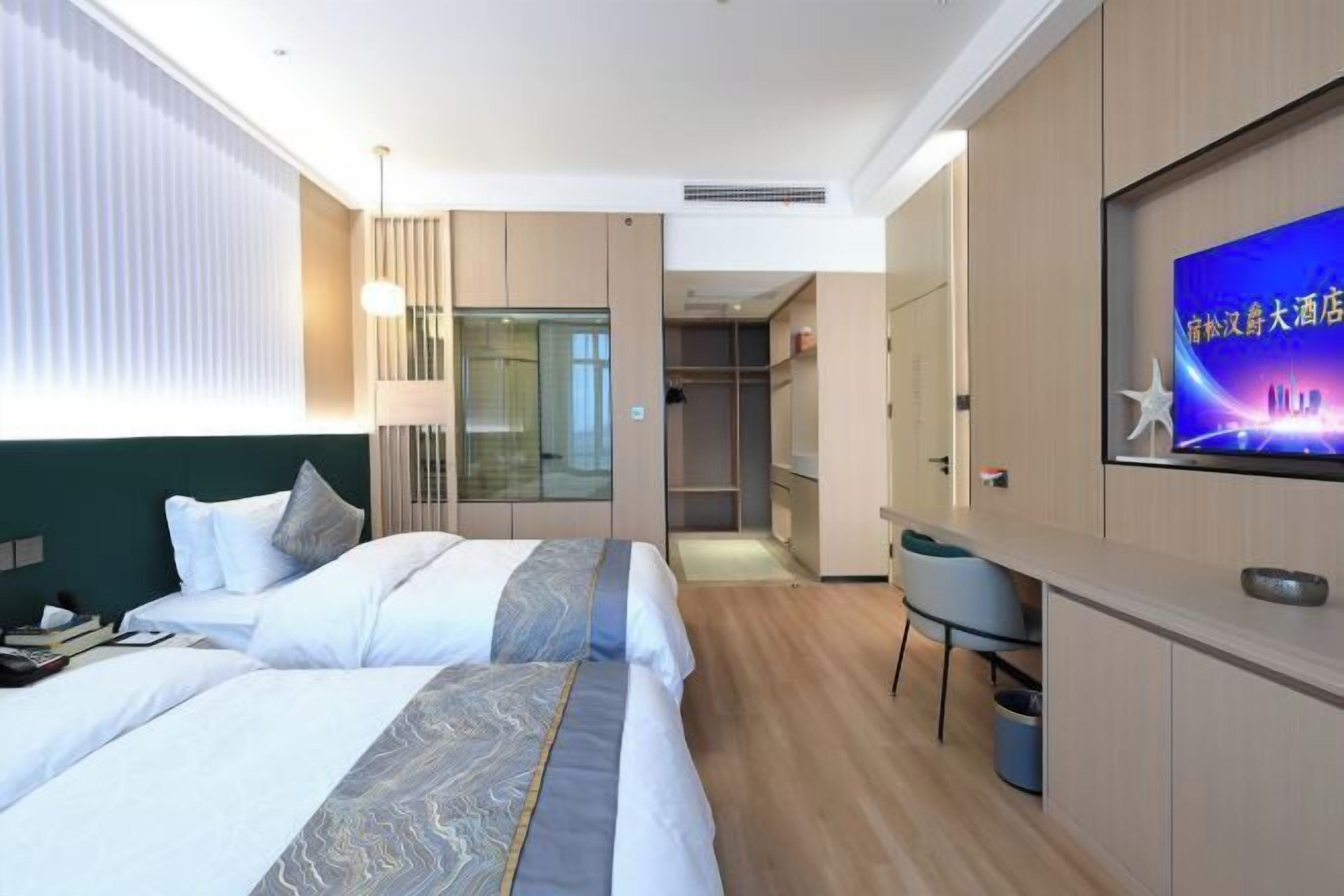 A hotel room with two beds, a TV, a desk, and a wardrobe.