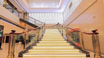 A multi-level interior with a central staircase, glass railings, and a modern ceiling design.