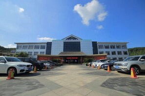 Un edificio con entrada central, varios espacios de estacionamiento y cielo despejado.