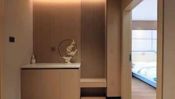 Una habitación de hotel moderna con un mostrador de recepción de madera, un jarrón decorativo y una cama con cabecera azul.