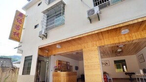 A building with a reception desk, wooden interior, and a signboard. - Yunshui Jingxiu Inn (Nanjing County)