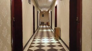 A hotel hallway with checkered flooring, wooden doors, and a reception desk. - Ximucuo Hotel (Jigzhi)