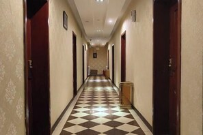 A hotel hallway with checkered flooring, wooden doors, and a reception desk. - Ximucuo Hotel (Jigzhi)