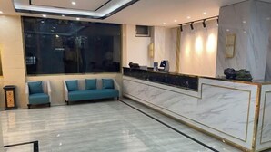 A hotel lobby with a marble reception desk, two sofas, a large window, and a modern ceiling design. - Ximucuo Hotel (Jigzhi)