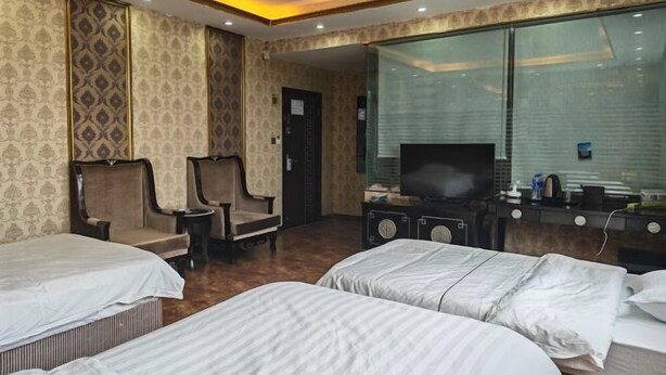 A hotel room with two beds, a TV, a desk, and a window. - Ximucuo Hotel (Jigzhi)