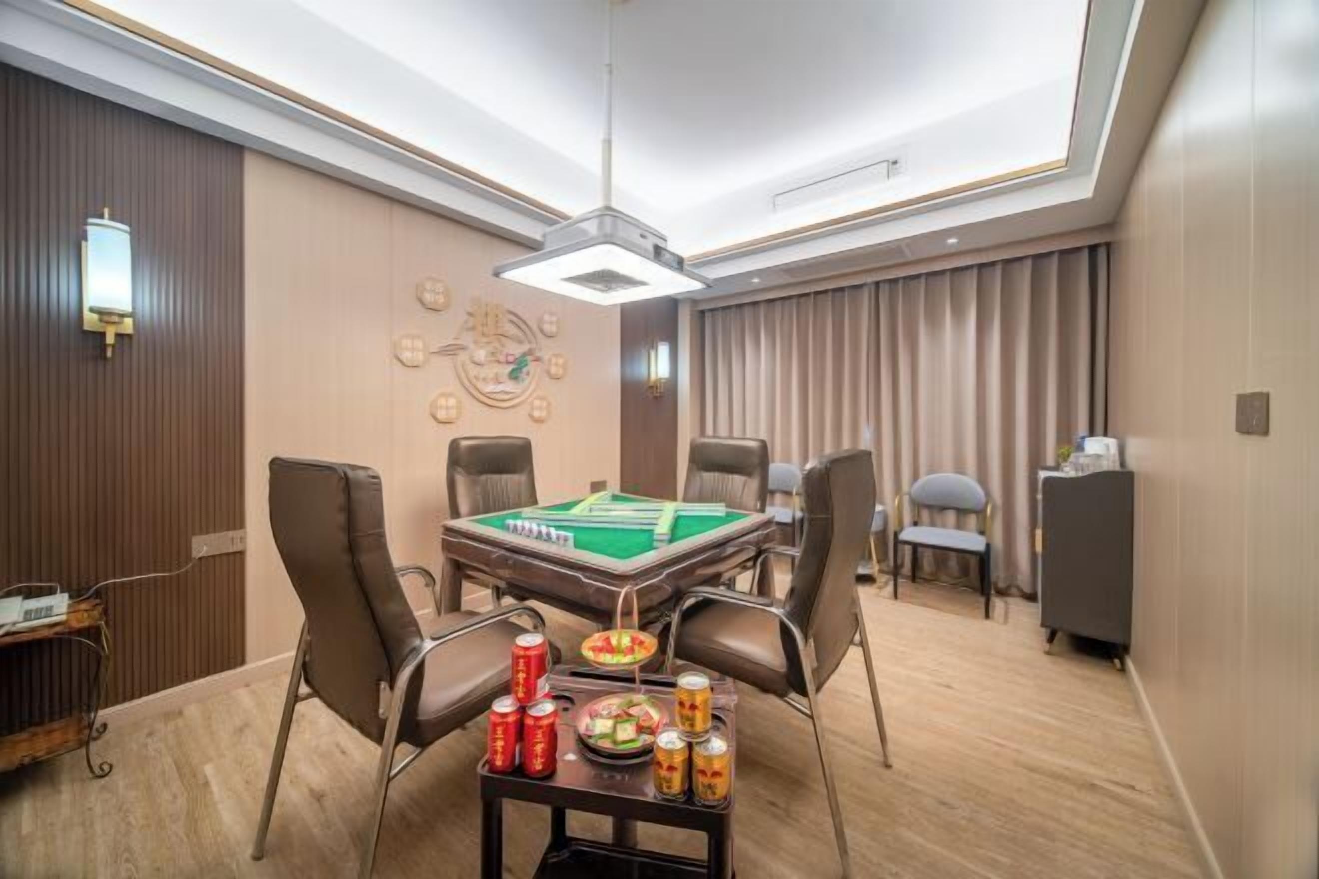 A room with a pool table, chairs, a small table with drinks, and a clock on the wall.