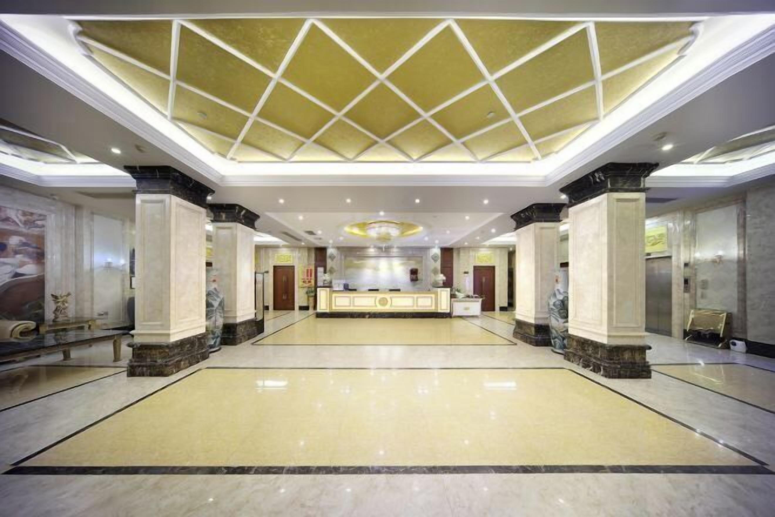 A spacious lobby with a high ceiling, marble flooring, and a reception desk.