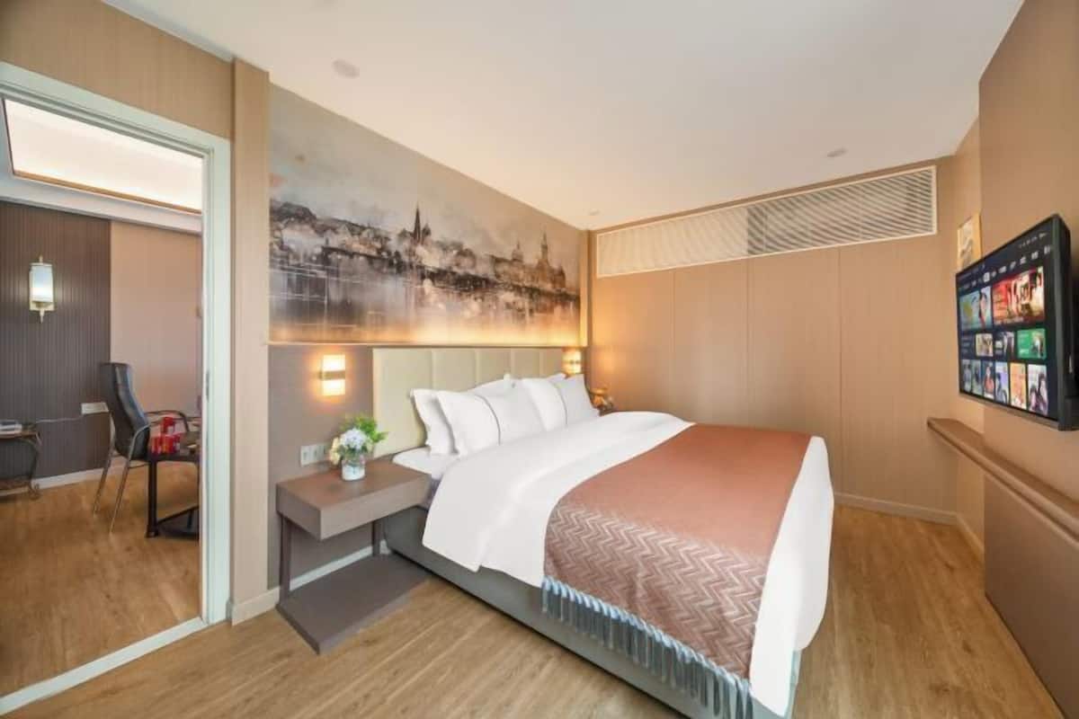 A hotel room with a bed, bedside table, and a wall-mounted TV.