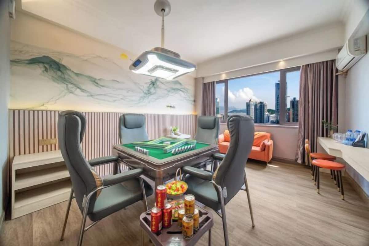 A hotel room with a pool table, gaming chairs, a city view, and a modern ceiling design.
