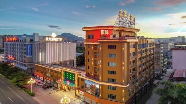 A multi-story hotel with a prominent sign on the top, a well-lit entrance, and a parking area in front. - Dongsheng Hotel（Puning International Commodity City · High-speed Rail Station Branch） (Puning)