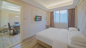 A hotel room with a bed, a desk with a chair, a television, and a window with curtains. - Dongsheng Hotel（Puning International Commodity City · High-speed Rail Station Branch） (Puning)
