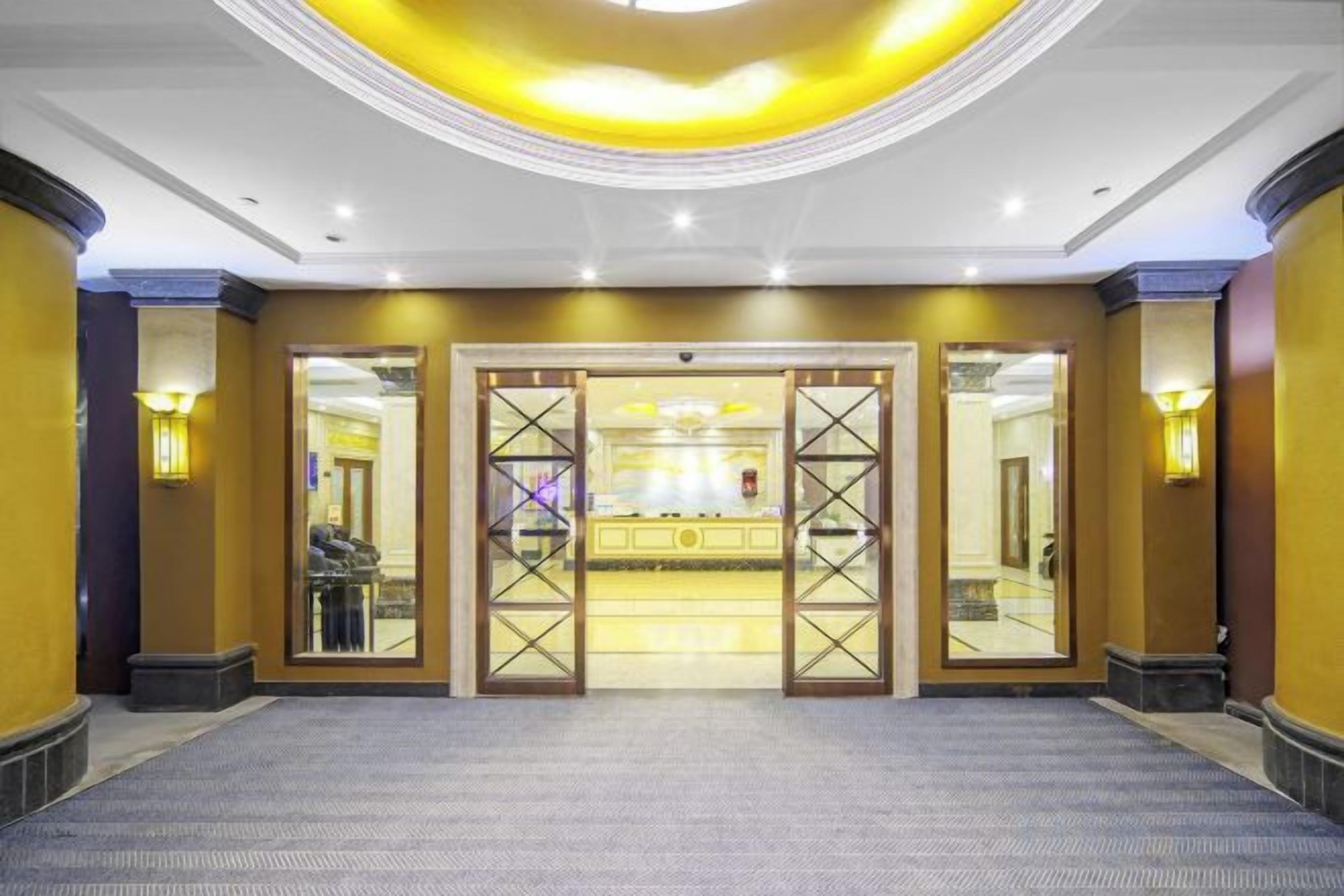 Eine Hotelhalle mit einer Rezeption, einem großen Spiegel und einem Teppichboden.