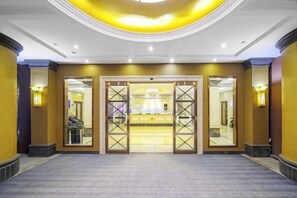 A hotel lobby with a reception desk, a large mirror, and a carpeted floor. - Dongsheng Hotel（Puning International Commodity City · High-speed Rail Station Branch） (Puning)
