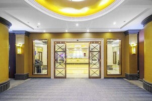 Un vestíbulo de hotel con una recepción, un espejo grande y suelo alfombrado.
