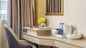 A hotel room with a desk, a chair, a vase with yellow flowers, a mirror, and a window with curtains. - Dongsheng Hotel（Puning International Commodity City · High-speed Rail Station Branch） (Puning)