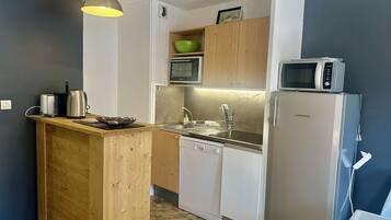 Een koelkast, een vaatwasser, kookgerei, borden en bestek