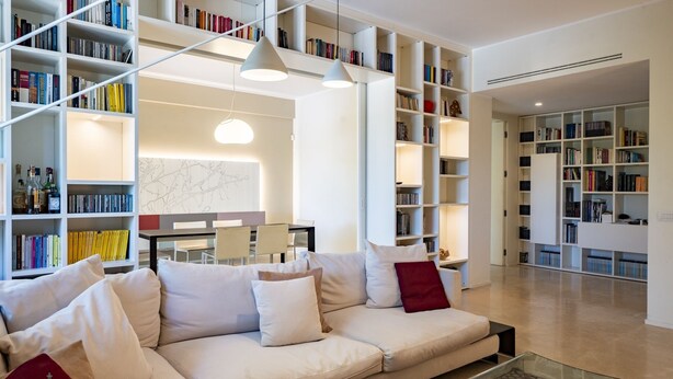 A modern living room with a white sofa, multiple bookshelves, and a dining area. - Domus Consalvi (Ponte Milvio): large design apartment - 3 bedrooms (Roma)