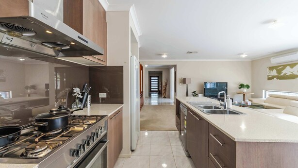 A modern kitchen with a central island, stainless steel appliances, and a view into the living area. - Elegant 4BR Villa with 3 Living Rooms in PointCook (Point Cook)