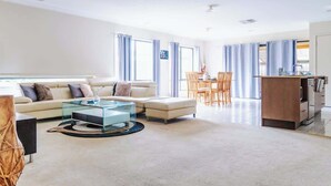 A modern living room with a sofa, coffee table, and dining area. - Elegant 4BR Villa with 3 Living Rooms in PointCook (Point Cook)