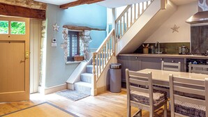 Una cocina moderna con escalera de madera, comedor y pared de piedra.