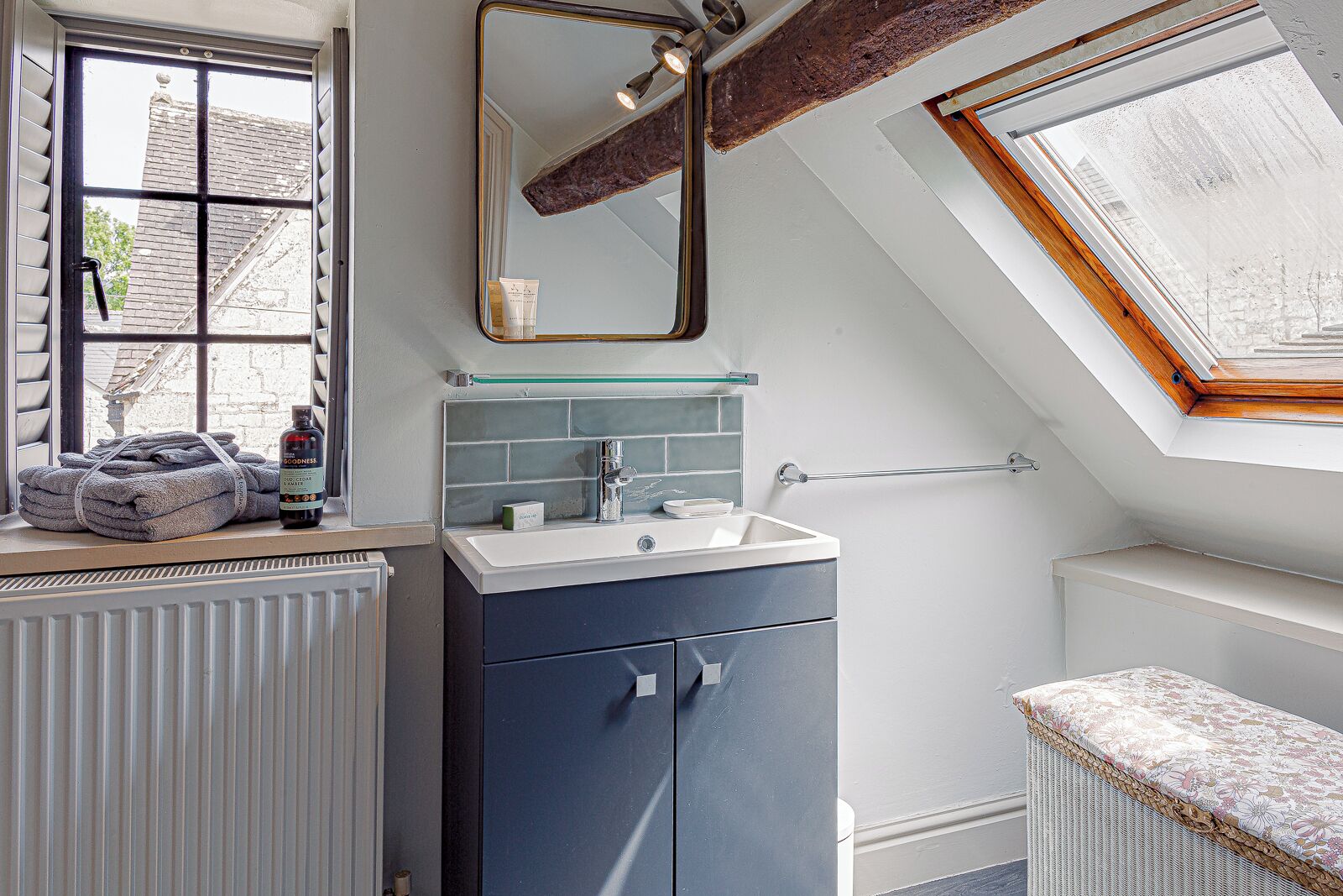 A modern bathroom with a skylight, a large mirror, and a window.