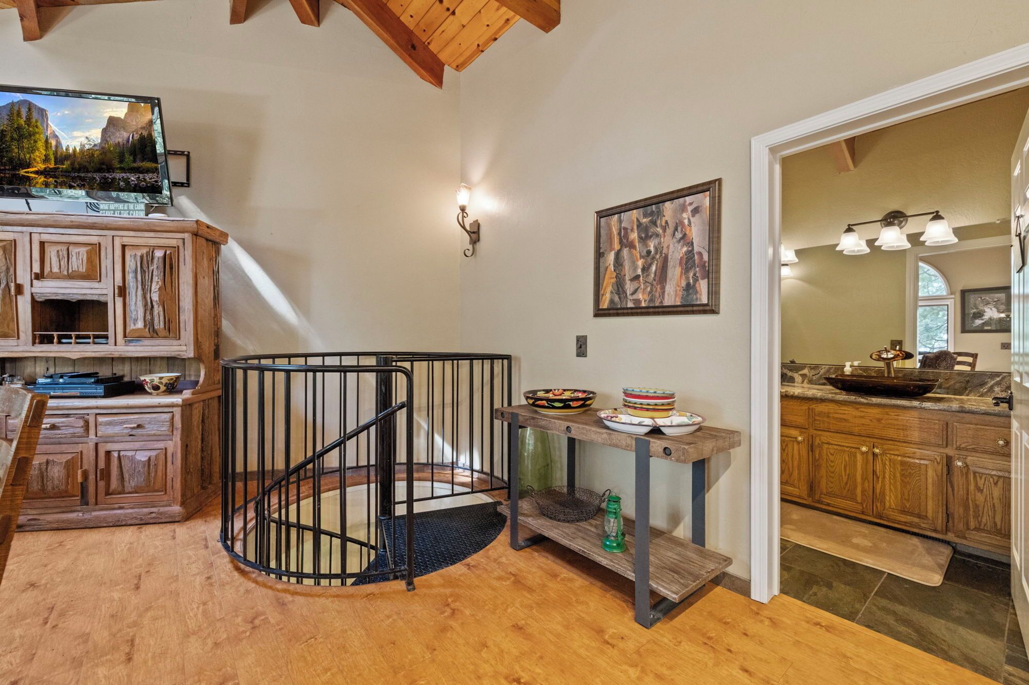 A wooden spiral staircase, a dining area with a wooden table and chairs, and a kitchen with wooden cabinets and a marble countertop.
