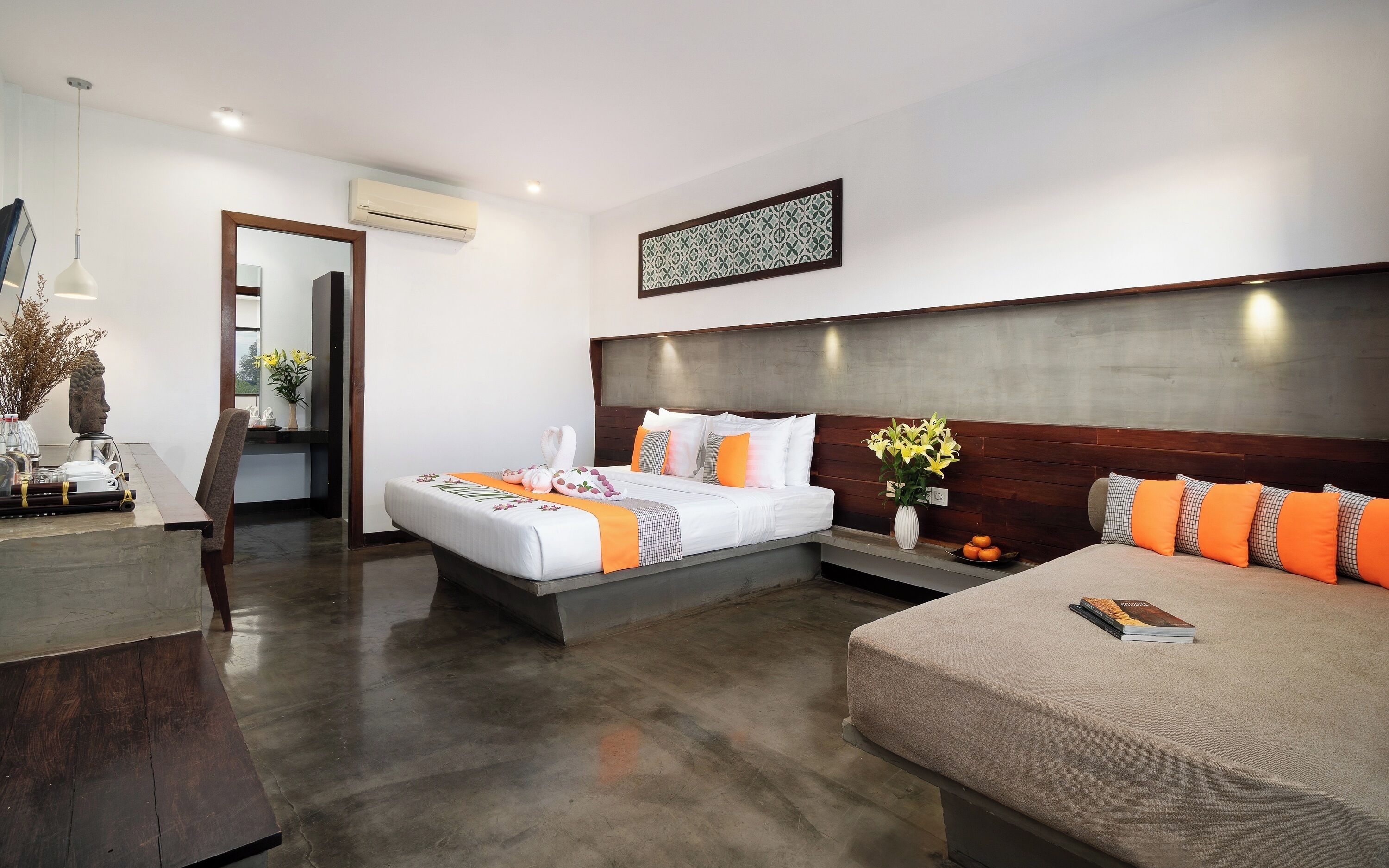 Une chambre d’hôtel moderne avec un grand lit, un petit canapé, un bureau et un miroir.