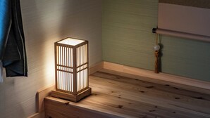 Una lámpara de pie de madera con una base cuadrada y listones verticales sobre un aparador de madera.