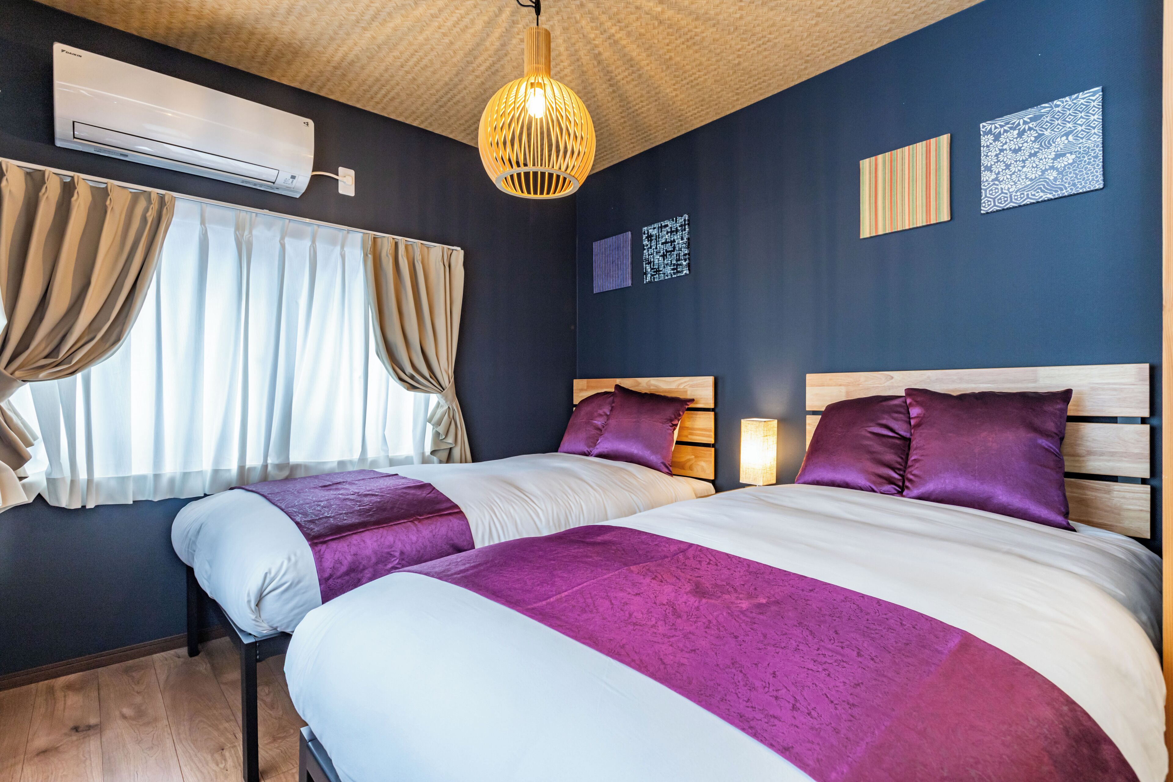 Une chambre d’hôtel avec deux lits, un ventilateur de plafond, un appareil de climatisation et des œuvres d’art murales.