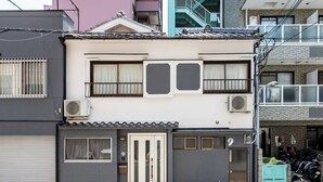 Un edificio de dos pisos con entrada por puerta corrediza, unidades de aire acondicionado y una bicicleta estacionada afuera.