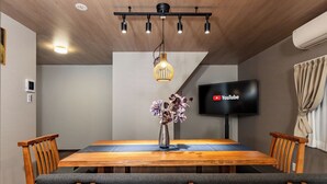 Un salón de conferencias con una mesa de madera, sillas tapizadas en gris, un jarrón con flores, una lámpara en el techo y un televisor de pantalla plana mostrando el logotipo de YouTube.