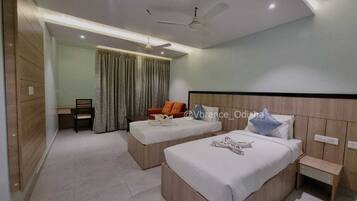 A modern bedroom with two beds, a desk, and a chair.