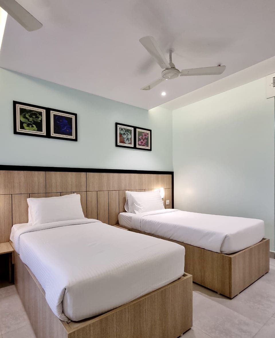 A hotel room with two beds, a ceiling fan, and wall-mounted artwork.